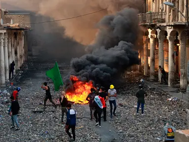 Demonstran antipemerintah membakar barang-barang saat pasukan keamanan menutup Rasheed Street selama bentrok di Baghdad, Irak, Kamis (28/11/2019). Sebanyak 27 demonstran antipemerintah tewas ditembak mati oleh pasukan keamanan Irak dalam sehari. (AP Photo/Khalid Mohammed)