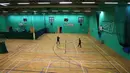 Orang-orang bermain bulu tangkis di aula olahraga dalam ruangan di pusat olahraga dan kebugaran The Pods yang kembali dibuka di Scunthorpe, Inggris timur laut, Senin (12/4/2021). Inggris melonggarkan pembatasan terkait virus corona COVID-19. (Photo by Lindsey Parnaby/AFP)