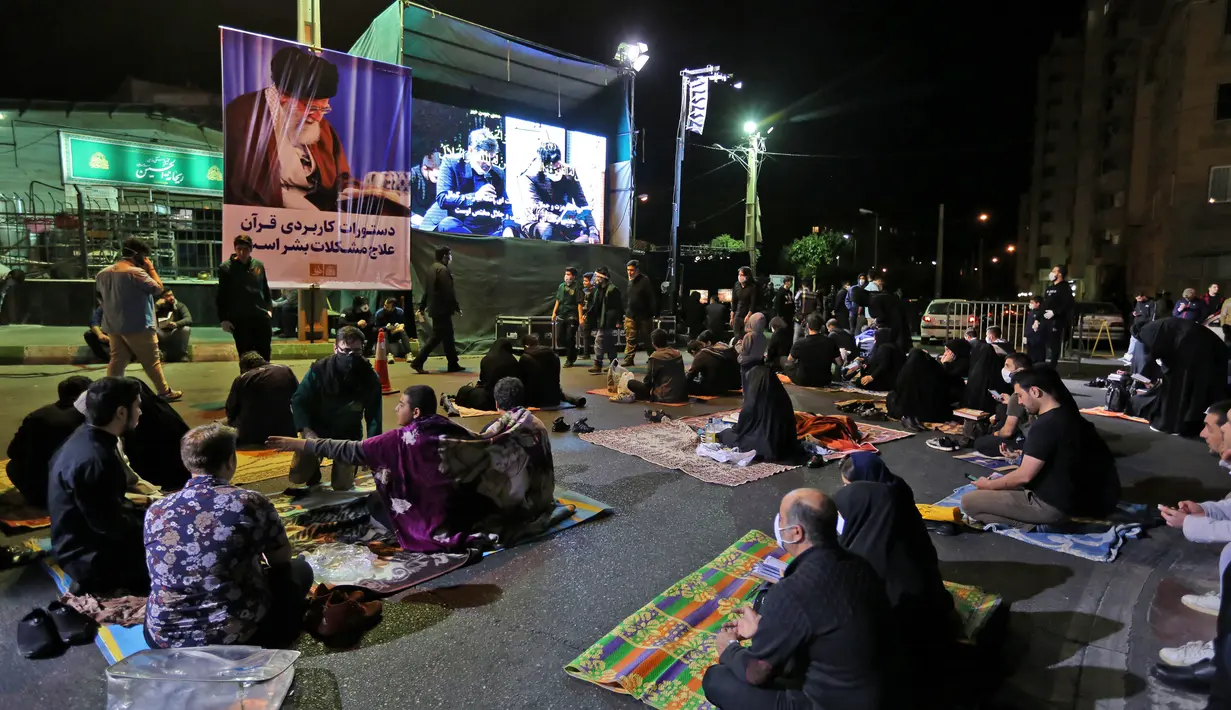 Warga Iran yang sebagian mengenakan masker menghadiri acara kajian dan pengajian Lailatul Qadar, salah satu malam paling suci selama bulan Ramadan, di luar masjid di Teheran, Rabu (13/5/2020). Pemerintah Iran membuka kembali masjid-masjid untuk manyambut malam Lailatul Qadar. (ATTA KENARE/AFP)