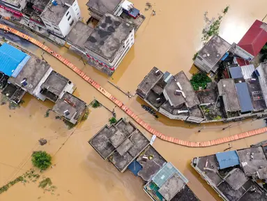 Foto ini menunjukkan pemandangan udara dari orang-orang yang melintasi jalan setapak yang dibangun di atas air banjir di sebuah jalan di kota Maying di Jiujiang, di provinsi Jiangxi Tengah, China, pada 3 Juli 2024. (Foto: AFP)