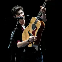 Shawn Mendes memang selalu identik dengan gitar akustik miliknya. (Liputan6.com/AFP)