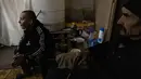 Hleb Petrova duduk di sebelah kakeknya di ruang bawah tanah di bawah pemadaman listrik di kota Bakhmut, Ukraina timur (22/12/2022). Mereka berkumpul untuk mengisi daya ponsel, makan dan menghangatkan diri sambil mencari perlindungan di tempat itu. (AFP/Sameer Al-Doumy)