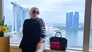 <p>Di foto lainnya, Syahrini juga masih menutup bagian perutnya dengan outer. Wanita berhijab itu berpose di kaca dengan pemandangan Marina Bay Sands. (foto: Instagram/ princessyahrini)</p>