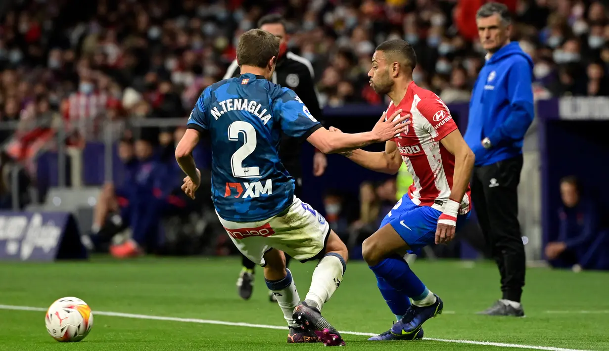 Bek Deportivo Alaves Nahuel Tenaglia (kiri) berebut bola dengan bek Atletico Madrid Renan Lodi dalam lanjutan La Liga Spanyol di Stadion Wanda Metropolitano, Minggu (3/4/2022) dinihari WIB. Atletico Madrid menang telak dengan skor 4-1 atas Deportivo. (JAVIER SORIANO / AFP)