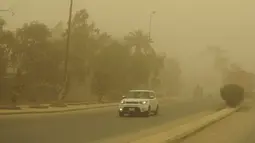 Pengemudi memasang lampu kabut mobil mereka saat mereka mengemudi selama badai pasir Musim Semi melalui ibukota Irak, Baghdad (5/5/2022). Irak kembali diselimuti lapisan jingga tebal karena mengalami serangkaian badai debu terbaru yang semakin sering terjadi. (AFP/Sabah Arar)