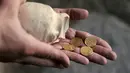 Arkeolog Israel Antiquities Authority, David Gellman menunjukkan kendi tembikar yang berisi empat koin emas murni di Yerusalem, Senin (9/11/2020). Kendi tembikar berusia 1.000 tahun berisi empat koin emas dari periode awal Islam itu ditemukan di dekat Plaza Tembok Ratapan. (MENAHEM KAHANA/AFP)