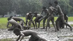 Anak-anak memainkan permainan Kabaddi di sebuah lahan yang digenangi air di Kolkata (8/9/2019). Kabaddi adalah olahraga yang berasal dari Tamil Nadu, India. (AFP Photo/Dibyangshu Sarkar)