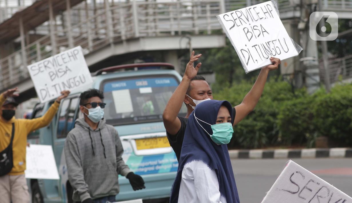 Penjual jasa perbaikan telepon genggam menawarkan jasa di pinggir jalan Mayjen Sutoyo depan Mall Pusat Grosir Cililitan (PGC), Jakarta, Rabu (14/7/2021). Imbas dari penutupan Mall PGC selama PPKM Darurat Jawa-Bali, mereka terpaksa menawarkan jasa di pinggir jalan. (Liputan6.com/Helmi Fithriansyah)