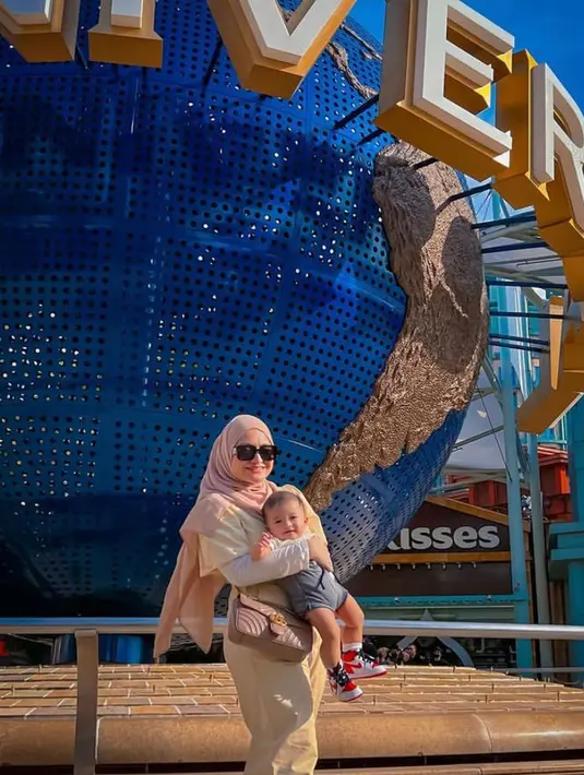 6. Berpose di Studio Universal bareng baby Adzam, Nathalie mengenakan baju overall dan hijab warna krem, dengan long sleeve putih. (Instagram/nathalieholscher).