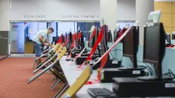Seorang staf yang memakai masker membersihkan komputer dan meja di sebuah perpustakaan di Toronto, Kanada (24/8/2020). Tahap ketiga rencana pembukaan kembali Perpustakaan Umum Toronto dimulai pada Senin (24/8). (Xinhua/Zou Zheng)