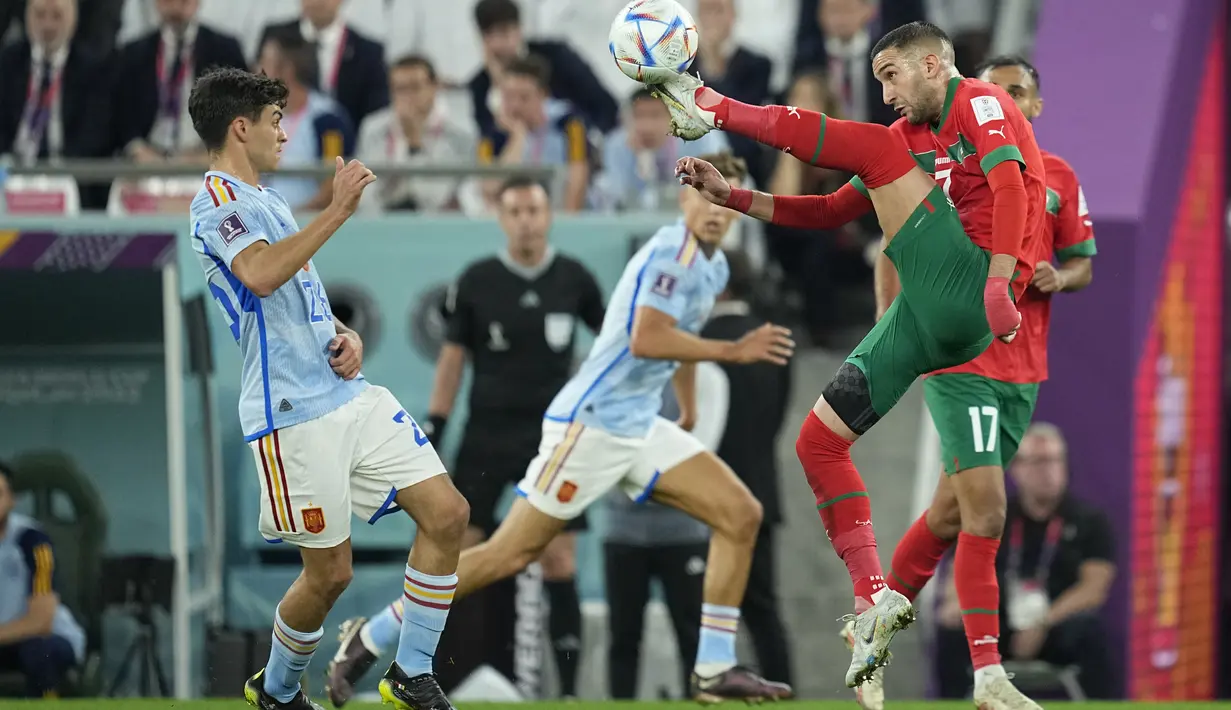 Gelandang Maroko Hakim Ziyech menendang bola di depan gelandang Spanyol Pedri pada babak 16 besar Piala Dunia 2022 di Education City Stadium, Al Rayyan, Rabu (6/12/2022) dini hari WIB. Singa Atlas kini berkesempatan mencatat sejarah. Mereka berpeluang menjadi wakil Afrika pertama yang mencapai semifinal Piala Dunia. (AP Photo/Ebrahim Noroozi)