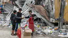 Anak-anak Palestina berjualan manisan pada hari kelima gencatan senjata sementara antara Hamas dan Israel di depan reruntuhan bangunan kamp pengungsi Jebaliya, Jalur Gaza, 28 November 2023. (AP Photo/Mohammed Hajjar)