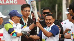 Petinju legendaris Indonesia, Nico Thomas, membawa obor Asian Games XVIII saat melintas di Kota Malang, Jawa Timur, Jumat (20/7/2018). Sebanyak 53 kota di Indonesia akan dilalui oleh obor Asian Games. (Bola.com/Aditya Wani)