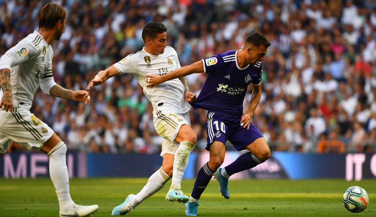 Gelandang Real Madrid, James Rodriguez, berebut bola dengan gelandang Valladolid, Oscar Plano, pada laga La Liga di Stadion Santiago Bernabeu, Madrid, Sabtu (24/8). Kedua klub bermain imbang 1-1. (AFP/Gabriel Bouys)