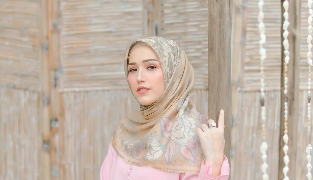 Padukan gamis berwarna pink pastel dengan hijab bermotif  berwarna coklat pastel seperti Adelia Pasha ini. [Instagram/adeliapasha]
