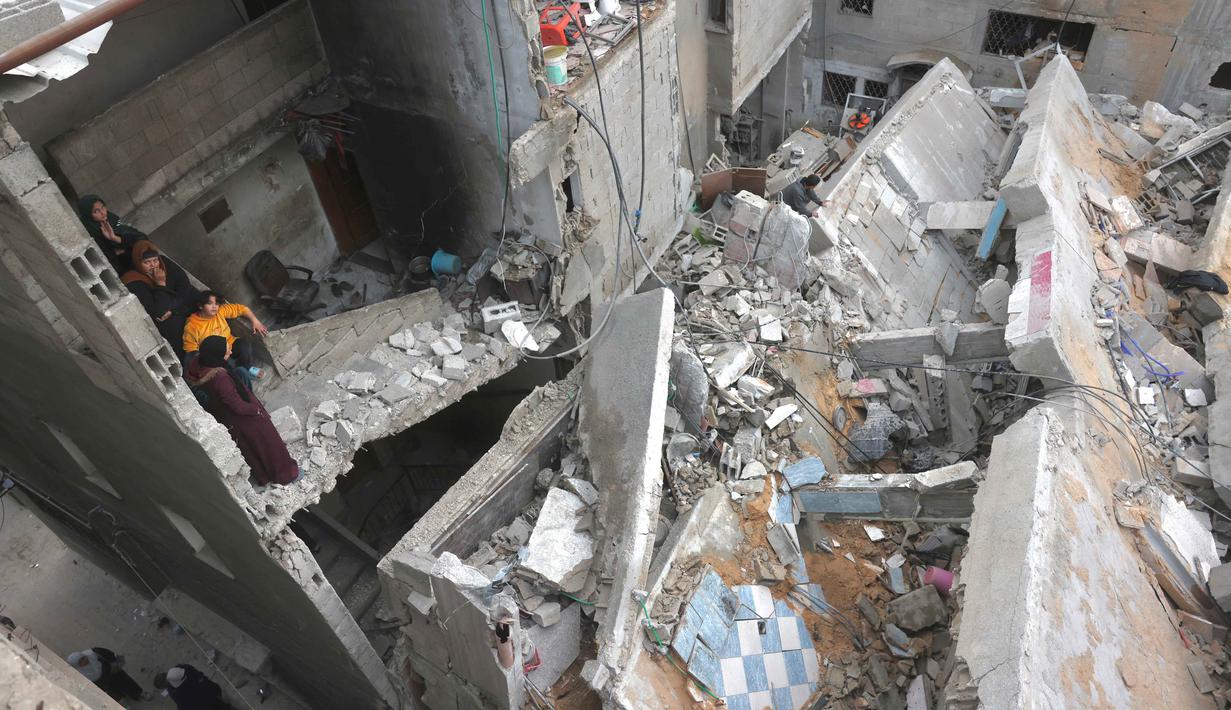 Militer Israel (IDF) berdalih serangan tersebut merupakan respons atas aksi penembakan terhadap pasukan mereka di perbatasan Gaza Utara. Tampak dalam foto, warga Palestina yang mengungsi memeriksa kerusakan setelah pesawat Israel menargetkan sebuah rumah berlantai lima tadi malam, di Khan Yunis, Jalur Gaza selatan, pada Kamis 6 Februari 2026. (Bashar Taleb/AFP)