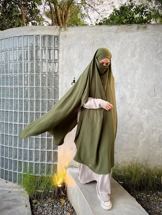 Potret lain memperlihatkan Zaskia mengenakan gamis bernuansa abu-abu dengan hijab syar’i berwarna hijau army lengkap dengan cadar. [Instagram/zaskiadyamecca]