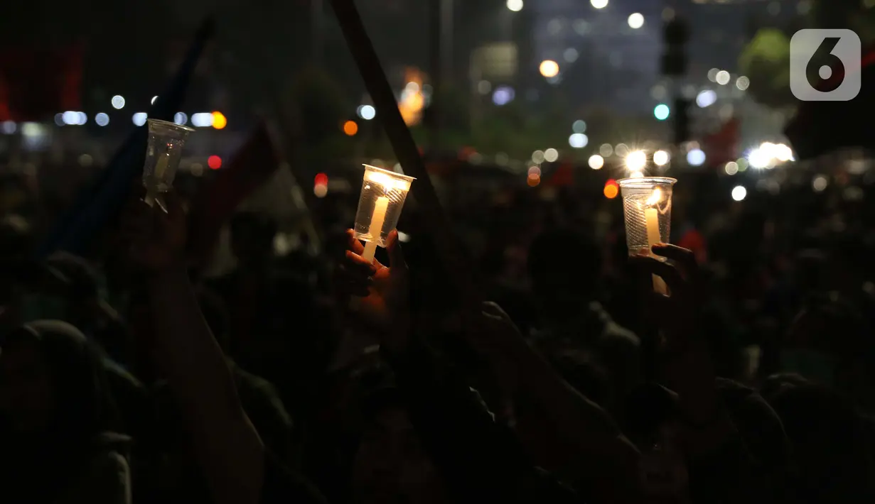 Peserta aksi unjuk rasa memegang lilin saat doa bersama lintas agama di Kawasan Patung Kuda, Jakarta, Selasa (10/11/2020). Sejumlah massa gabungan dari berbagai organisasi buruh dan mahasiswa berunjuk rasa menolak pengesahan Omnibus Law UU Cipta Kerja. (Liputan6.com/Helmi Fithriansyah)