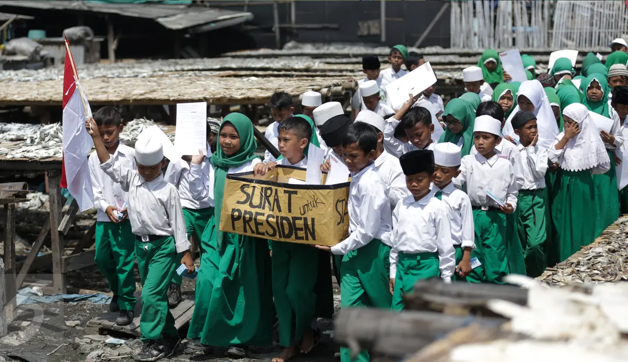 Murid MI Yayasan Nurul Bahri melakukan pawai usai menulis surat untuk Presiden Jokowi, di perkampungan nelayan Muara Angke, Jakarta, Senin (27/2). Kegiatan itu juga sebagai kepedulian pada dunia literasi untuk anak Indonesia. (Liputan6.com/Faizal Fanani)