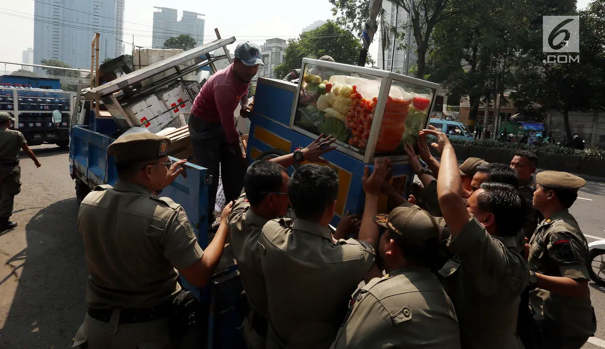 Petugas Satpol PP mengangkut gerobak milik pedagang buah keliling saat merazia pedagang kaki lima di kawasan Karet, Jakarta, Senin (17/7). Razia itu untuk membuat jera pedagang yang nakal dan tetap nekat berjualan di bahu jalan. (Liputan6.com/Johan Tallo)