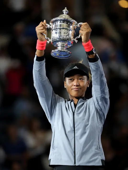 Petenis Jepang, Naomi Osaka mengangkat trofi turnamen AS Terbuka setelah mengalahkan petenis AS, Serena Williams pada partai final di Arthur Ashe Stadium, New York, Sabtu (8/9). Naomi Osaka menang dua set dengan skor 6-2 dan 6-4. (ELSA/GETTY IMAGES/AFP)