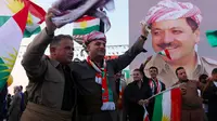 Warga Kurdi Irak berkumpul sambil melambai-lambaikan bendera Kurdi di samping poster Pemimpin Kurdi, Massoud Barzani saat melakukan aksi untuk meminta referendum kemerdekaan di Arbil, Irak utara (13/9). (AFP Photo/SAfim Hamed)