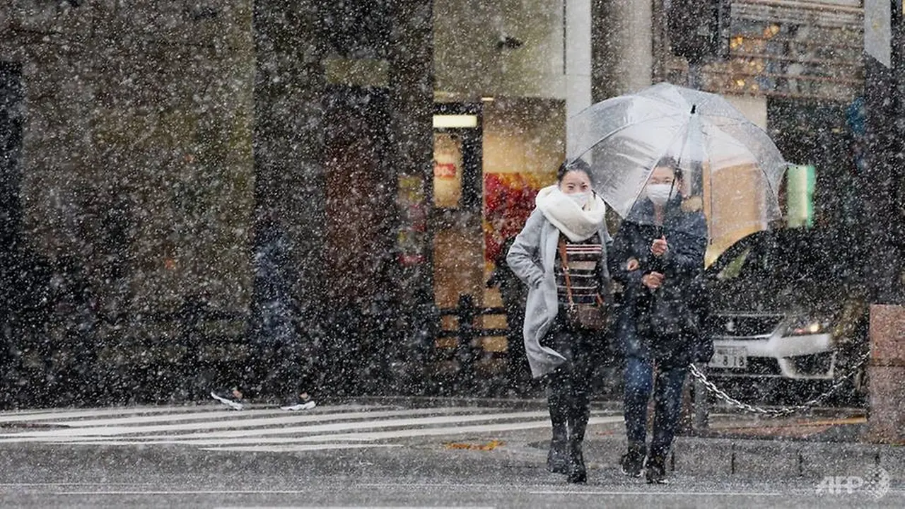 Pejalan kaki berjalan di jalan saat salju turun di Fukuoka pada 30 Des 2020. (Foto: AFP / Jiji Press)