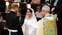 Pangeran Harry dan Meghan Markle saling berpandangan saat prosesi pernikahan mereka di Kapel St. George, Kastil Windsor, Inggris, Sabtu (19/5). Pangeran Harry dan Meghan Markle resmi menjadi suami istri. (Dominic Lipinski/POOL/AFP)