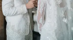 Angga terlihat tampan dalam balutan setelan pengantin putih. Shenina juga tampak anggun dengan gaun pernikahan elegan. Senyum Angga menunjukkan kebahagiaan yang terpancar jelas di hari pernikahan, menandai dirinya sudah resmi menyandang status sebagai suami. (Liputan6.com/IG/@angga)