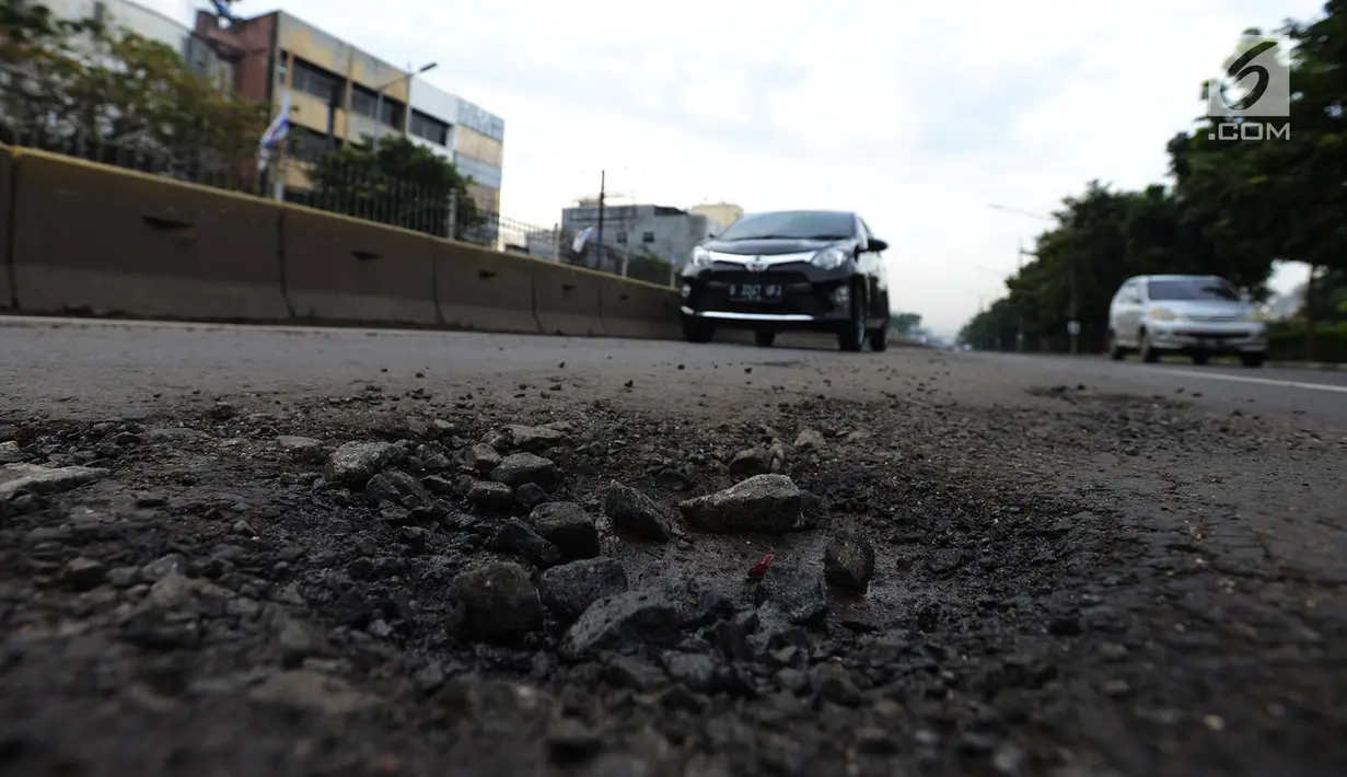 Kendaraan melintasi jalan berlubang di Jalan Gunung Sahari, Jakarta, Selasa (9/4). Meskipun sudah dilakukan penambalan, jalan raya tersebut sering rusak akibat beban kendaraan yang melintas di atasnya dan intensitas hujan yang belakangan ini cukup tinggi. (merdeka.com/Imam Buhori)