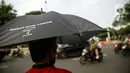 Anggota Jaringan Solidaritas Korban untuk Keadilan (JSKK) menggunakan payung hitam bertuliskan "Jangan Diam, Lawan!" saat melakukan Aksi Kamisan ke-795 di seberang Istana Merdeka, Jakarta, Kamis (16/11/2023). (Liputan6.com/Faizal Fanani)