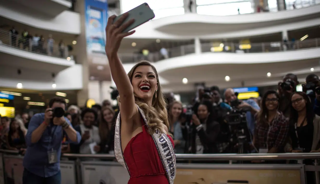 Miss Universe 2017 asal Afrika Selatan, Demi-Leigh Nel-Peters berselfie dengan awak media saat tiba di Bandara Internasional OR Tambo di Johannesburg (24/1). (AFP Photo/Gulshan Khan)