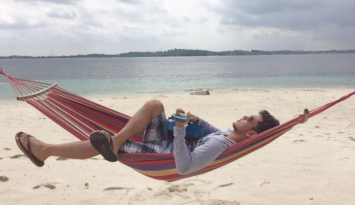 Pemeran Bambang di Diam-Diam Suka ini menikmati pantai White Sand Island di Riau. Sambil tertidur di hammock, pria yang akrab disapa Rangga ini menikmati suasana pantai. (Liputan6.com/IG/@azofrangga)