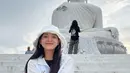 Kim Se Jeong saat berfoto di depan patung Budha yang besar, Ia tampak sangat flawless dengan topi putihnya. (Instagram/clean_0828)