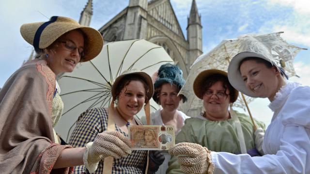 Orang-orang mengenakan kostum masa lampau berpose dengan uang kertas sepuluh pound baru Bank of England, yang menampilkan penulis Jane Austen, selama peluncurannya di Katedral Winchester di Winchester, Inggris selatan, pada tanggal 18 Juli 2017.