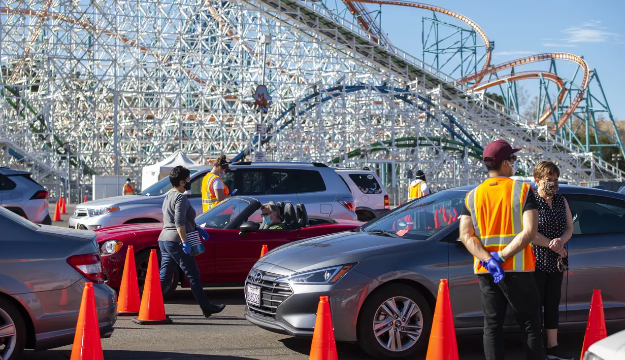 Orang-orang duduk di dalam mobil mereka di area observasi untuk memeriksa kemungkinan efek samping setelah mendapatkan suntikan vaksin di pusat vaksinasi Covid 19 skala besar yang didirikan di Six Flags Magic Mountain di Valencia, California, Selasa (2/2/2021). (VALERIE MACON/AFP)