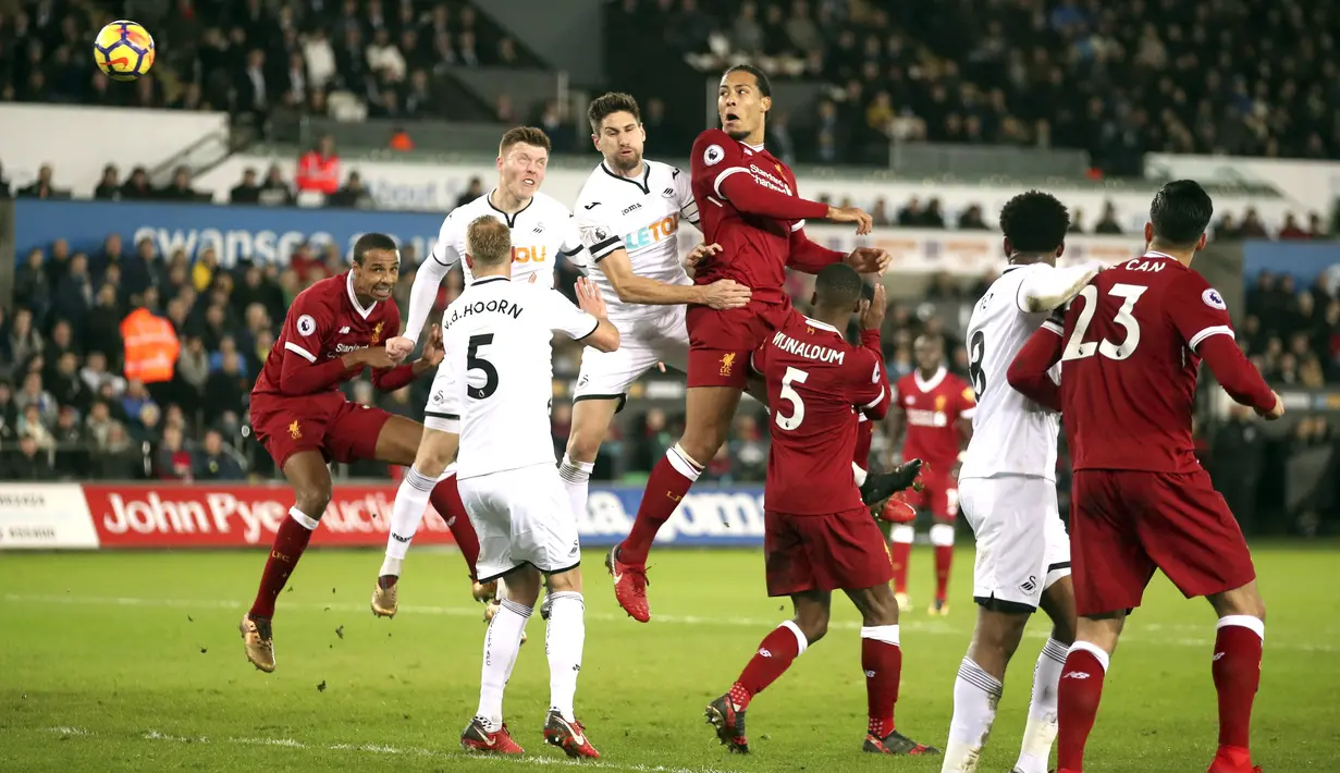 Pemain Liverpool, Virgil van Dijk (tengah) menyundul bola melewati adangan para pemain Swansea City ,pada lanjutan Premier League di Liberty Stadium, Swansea, (22/1/2018). Liverpool kalaj dari Swansea 0-1.  (Nick Potts/PA via AP)