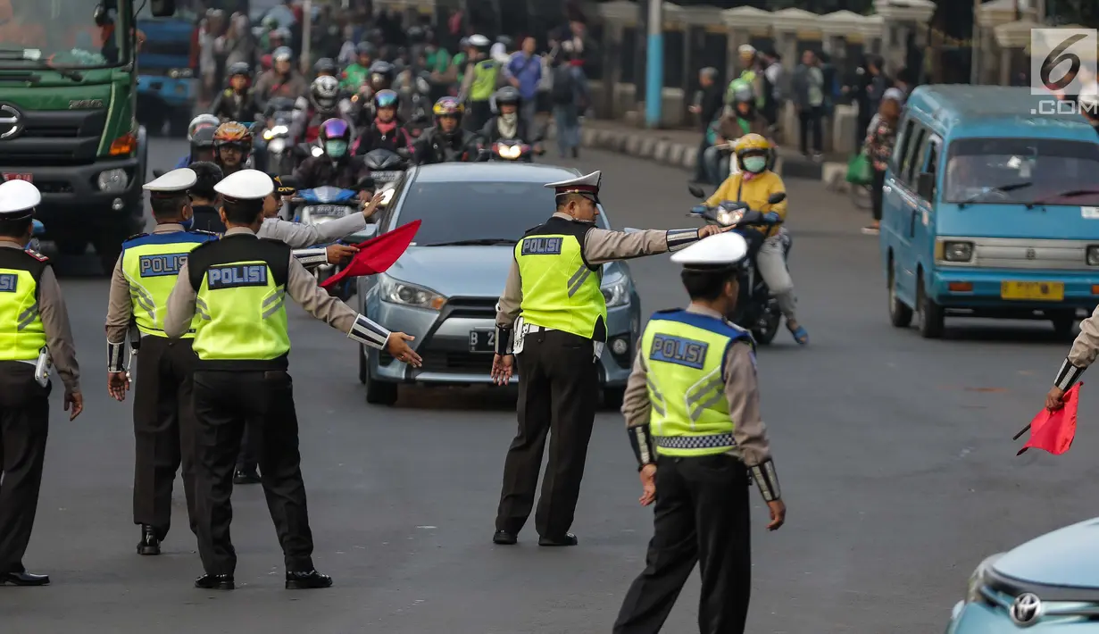 Petugas polisi lalu lintas memberi arahan kepada pengguna mobil saat pemberlakuan sistem ganjil genap di pintu masuk Gardu Tol Cibubur 2, Jakarta, Senin (16/4). (Liputan6.com/Faizal Fanani)