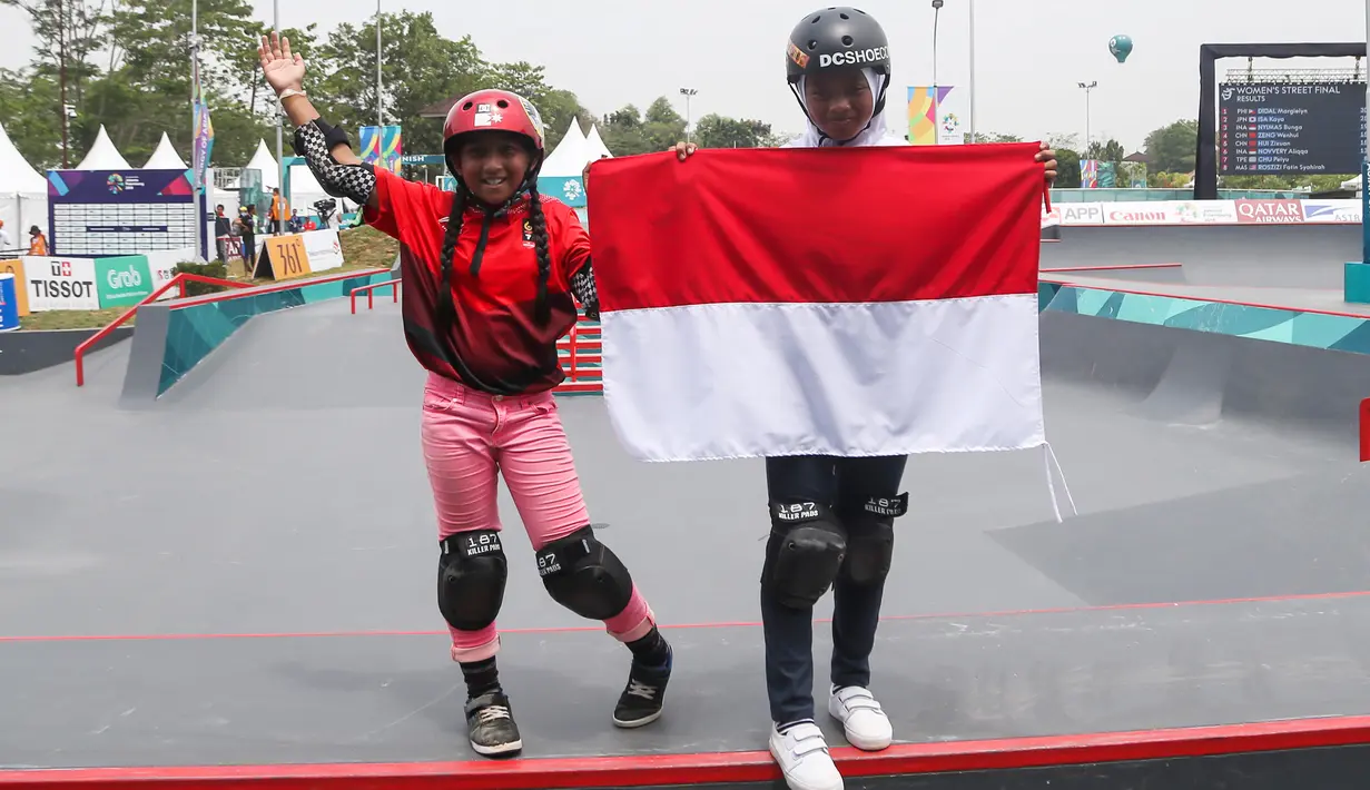 Skateboarder putri Indonesia Aliqqa Novvery (kiri) dan Bunga Nyimas mengibarkan bendera merah putih usai mengikuti final skateboard kelas taman putri Asian Games 2018 di Palembang, Sumatera Selatan, Rabu (29/8). (ANTARA FOTO/INASGOC/M N Kanwa/thv/18)