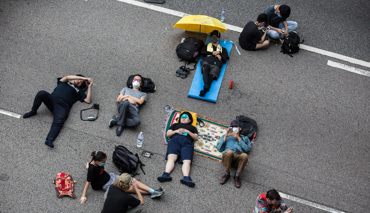 Sejumlah pengunjuk rasa tidur di jalanan saat menggelar protes terkait RUU Ekstradisi di Hong Kong, Senin (17/6/2019). Pengunjuk rasa mengenakan pakaian hitam saat menggelar unjuk rasa menentang RUU Ekstradisi. (ISAAC LAWRENCE/AFP)
