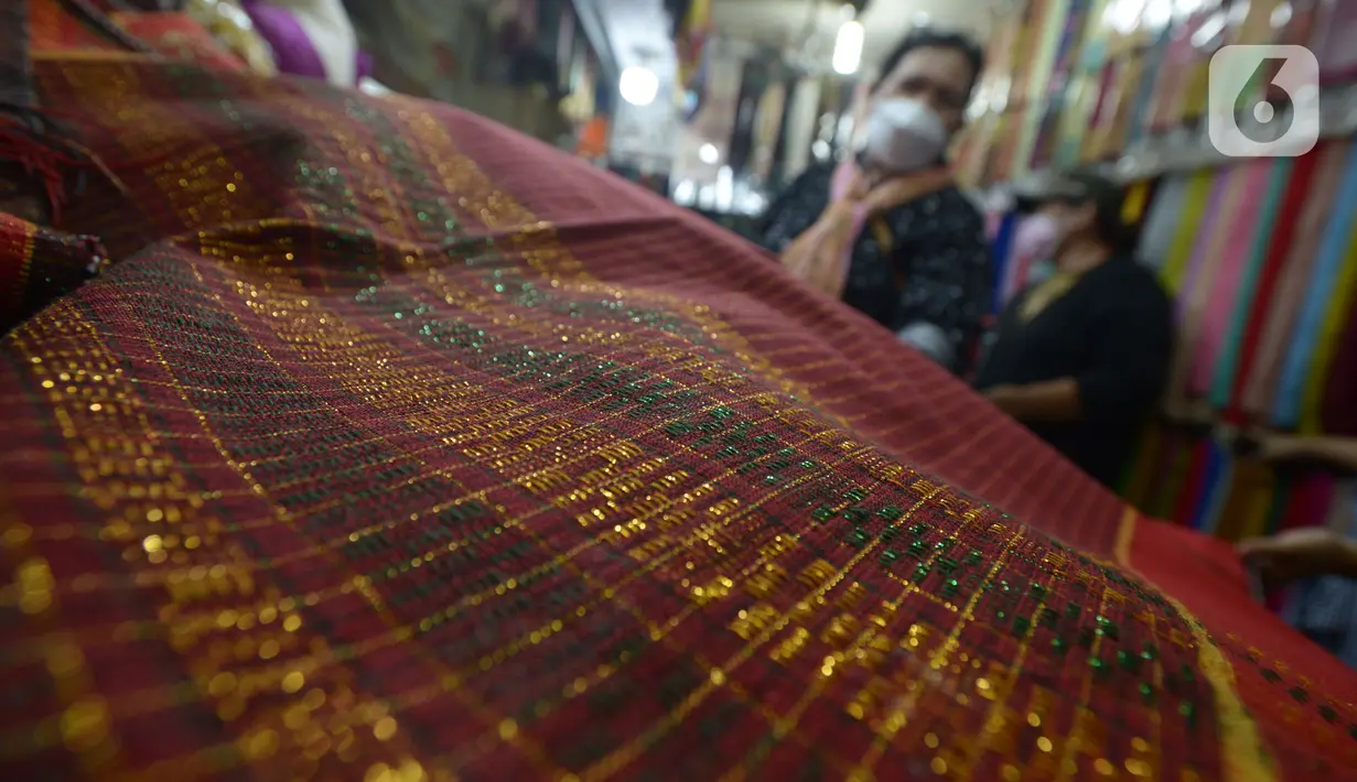 Aktivitas jual beli kain ulos di pasar proyek Senen, Jakarta, Kamis (21/10/2021). Sejak status PPKM turun dari level 3 menjadi level 2, pengunjung ramai mendatangi toko membeli kain ulos untuk upacara pernikahan adat dengan kisaran harga dari Rp. 500.000 hingga jutaan rupiah. (merdeka.com/Imam Buhor