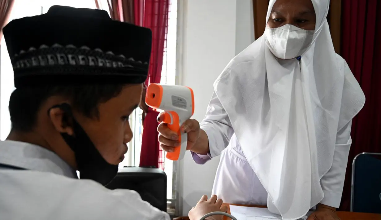 Seorang siswa sekolah menengah pertama menjalani pemeriksaan suhu tubuh sebelum menerima dosis vaksin Sinovac pada acara vaksinasi virus corona COVID-19 di Blang Bintang, Provinsi Aceh, 21 September 2021. (CHAIDEER MAHYUDDIN/AFP)