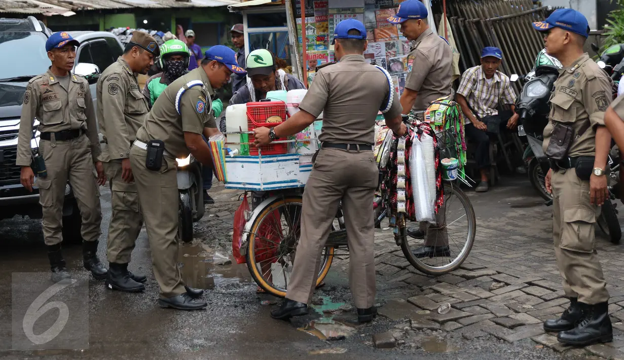 Petugas Satpol PP menahan barang dagangan milik pedagang kopi keliling yang berjualan di kawasan SCBD, Jakarta, Senin (21/11). Satpol PP merazia dan menyita dagangan yang beroperasi di kawasan tersebut. (Liputan6.com/Gempur M Surya)