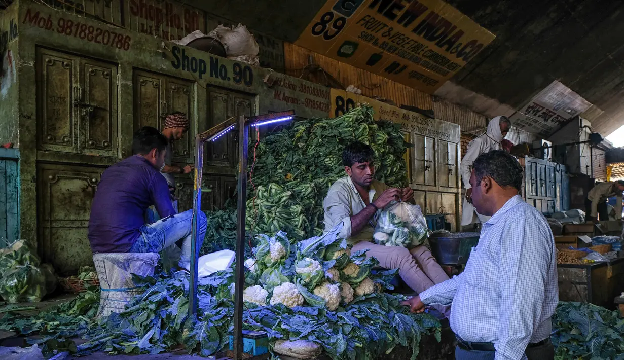 Seorang pria membeli membeli kembang kol di pasar grosir buah dan sayuran di New Delhi, India (27/3). Pasar jalanan Delhi dilaporkan memberikan omset lebih besar dibandingkan dengan mal. (AFP Photo/Noemi Cassanelli)