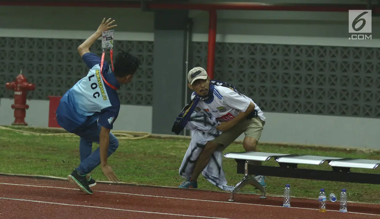 Petugas LOC berusaha mencegat suporter tim Maung Bandung masuk lapangan usai laga Bhayangkara FC melawan Persib di Stadion Patriot Candrabhaga, Bekasi, Minggu (4/6). Persib kalah 0-2 dari Bhayangkara FC. (Liputan6.com/Helmi Fithriansyah)