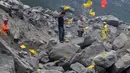 Keluarga korban melemparkan kertas ritual untuk menenangkan arwah orang yang tewas di lokasi tanah longsor di desa Xinmo, Sichuan, China (25/6). Sekitar 118 orang hilang diduga tertimbun bebatuan akibat longsor ditempat tersebut. (AP Photo / Ng Han Guan)
