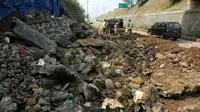 Pekerja membersihkan sisa longsoran di bahu Jalan Tol Bogor Ring Road (BORR) di Bogor, Jabar, Senin (4/7). Longsor tersebut diakibatkan hujan deras yang melanda Bogor.(Antara)