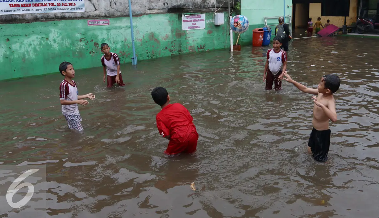 Beberapa anak bermain bola diatas genangan air di kawasan Jatayu, Jakarta, Senin (21/11). Genangan air di kawasan ini mencapai 50 cm hingga 100 cm. (Liputan6.com/Gempur M. Surya)