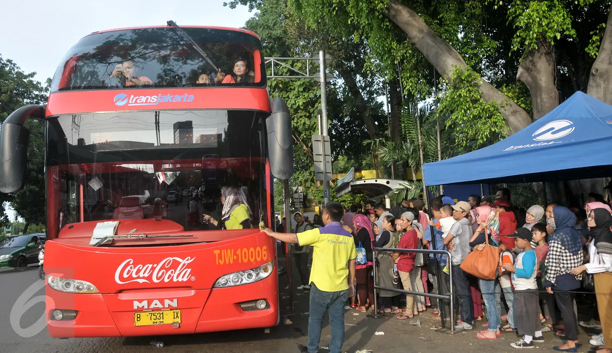 Antrean penumpang menaiki bus tingkat wisata di depan halte Masjid Istiqlal, Jakarta, Minggu (30/4). Warga memanfaatkan hari libur panjang mereka dengan berkeliling Jakarta menggunakan bus tingkat ini secara gratis. (Liputan6.com/Yoppy Renato)