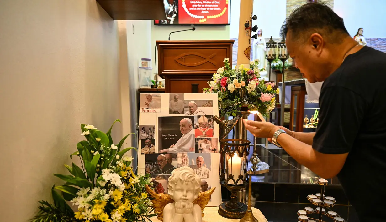 Pastor Clement dari Malaysia menyalakan lilin menjelang misa yang diadakan untuk mengenang Paus Fransiskus di Gereja Hati Kudus di Bentong pada 21 April 2025. (MOHD RASFAN/AFP)